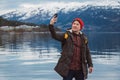 Traveler man taking self-portrait a photo with a smartphone. Tourist in a yellow backpack standing on a background of a Royalty Free Stock Photo