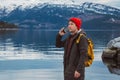 Traveler man talking on mobile phone. Tourist in a yellow backpack standing on a background of a mountain and a lake Royalty Free Stock Photo
