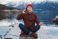 Traveler man talking on mobile phone. Tourist in a yellow backpack standing on a background of a mountain and a lake Royalty Free Stock Photo