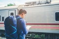Traveler man using tablet and waits train on railway platform