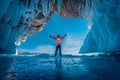 Traveler man wear red clothes and raising arm standing on frozen water in ice cave at Lake Baikal, Siberia, Russia Royalty Free Stock Photo