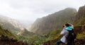 Traveler on the mountain edge making a photo of landscape. Deep clouds above green Xo-Xo Valley. Santo Antao Island