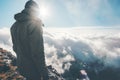 Traveler on mountain summit with sun over clouds