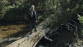 Traveler photographing scenic view in forest river. Wood bridge fallen tree. One caucasian woman shooting nice magic