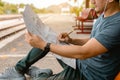 Traveler is planning vacation and looking the map at railway station. Man is writing notes and pointing on the map Royalty Free Stock Photo