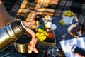 Traveler pouring hot tea from thermos to cup at autumn fallen forest outdoor Royalty Free Stock Photo