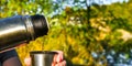 Traveler pouring hot tea from thermos to cup at autumn fallen forest outdoor Royalty Free Stock Photo