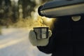 Traveler pours hot tea from a thermos into a mug, walking in snowy frozen winter forest