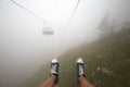 Traveler ride mountain cableway stretching down over beautiful early autumn mountain landscape in deep fog. First person