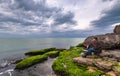 Traveler on a rocky seashore overgrown with green algae