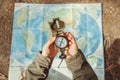 Traveler searching direction with a compass on background of map