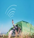 Traveler sits in touristic camping tent and tries to catch cellular network. Cell web coverage and roaming concept image.