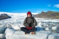 Traveler sitting on small ice shelf and doing meditation
