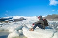 A traveler sitting on small ice at Fjallsarlon Glacier Lagoon in Southeast Iceland