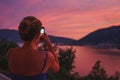 Traveler smartphone landscape photography. Girl takes magical colorful sunset story smartphone traveling mountains Montenegro.