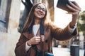 Traveler smile in glasses self cellphone internet technology in europe trip. Tourist girl taking photo selfie on smartphone online