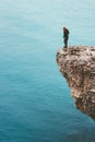 Traveler standing on cliff edge above sea alone Travel Lifestyle concept adventure