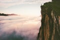 Traveler standing on cliff edge mountain top above sunset clouds Royalty Free Stock Photo