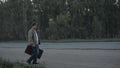 Traveler with a suitcase limping on a country road