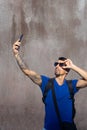 Traveler with tattoos in the arms, lost connectivity and have bad signal in his telephone and hold his sunglasses, search.