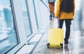 Traveler tourist in bright jacket with yellow suitcase backpack at airport on background large window blue sky, man waiting in dep Royalty Free Stock Photo