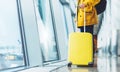 Traveler tourist with yellow suitcase backpack at airport on background large window blue sky, man in bright jacket waiting Royalty Free Stock Photo