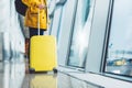 Traveler tourist with yellow suitcase backpack at airport on background large window, man in bright jacket waiting in departure Royalty Free Stock Photo