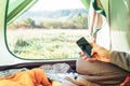 Traveler uses mobile phone sitting in tent. Close up image man h Royalty Free Stock Photo