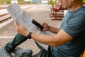 Traveler is using smartphone while planning vacation with map at railway station. Man is planning vacation and looking the map Royalty Free Stock Photo