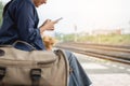 Traveler is waiting for train at the railway station. Women using smartphone for waiting train station platform