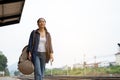 Traveler is walking alone with a backpack at train station. Women is walking along a railway platform