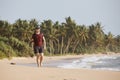 Traveler walking on idyllic beach with palm trees