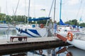 Man on vacation walking in river marina near of white boats with folded sails. Young fashionable man start river journey