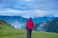 Traveler walks through the alpine meadow to the cliff Royalty Free Stock Photo