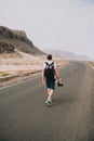 Traveler walks in the center of an epic winding road. Huge volcanic mountains in the distance behind him. Sao Vicente