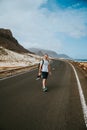 Traveler walks in the center of an epic winding road. Huge volcanic mountains in the distance behind him. Sao Vicente