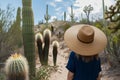 traveler in widebrimmed hat observing cacti on a desert trail Royalty Free Stock Photo