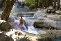 Traveler woman enjoy on stone at Erawan Waterfal