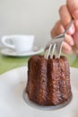 Traveler woman hand holding a fork and cutting a CanelÃÂ© Canele - Caneles de bordeaux traditional French sweet dessert bakery