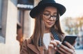 Traveler woman holding in hands mobile phone. Technology smartphone online connect. Portrait girl tourist in glasses using gadget Royalty Free Stock Photo