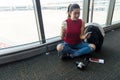 Traveler woman plan and backpack checking board pass at the airport glass window, girl tourist hold bag and waiting near luggage i Royalty Free Stock Photo