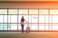 Traveler woman plan and backpack see the airplane at the airport glass window, girl tourist hold bag a Royalty Free Stock Photo