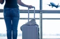 Traveler woman plan and backpack see the airplane at the airport glass window, girl tourist hold bag and waiting near luggage in h Royalty Free Stock Photo