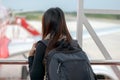 Traveler woman plan and backpack see airplane flight at the airport glass window, girl tourist happy hold bag and waiting luggage Royalty Free Stock Photo