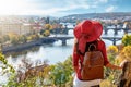 A traveler woman with red hat enjoys the elevated view over the city of Prague, Czech Republic