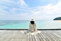 Traveler woman relaxing and sitting on wooden jetty by the clear blue sea. Royalty Free Stock Photo