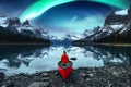 Traveler woman sitting on canoe with aurora borealis over Spirit Island in Maligne lake at Jasper national park Royalty Free Stock Photo