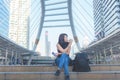 Traveler woman sitting and drinking coffee in paper cup on staircase in city town, urban background, street style,