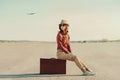 Traveler woman sitting on suitcase on road Royalty Free Stock Photo