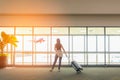 Traveler woman standing and hand holding luggage bag see the airplane at the airport glass window. Tourist waiting in hall airpla Royalty Free Stock Photo